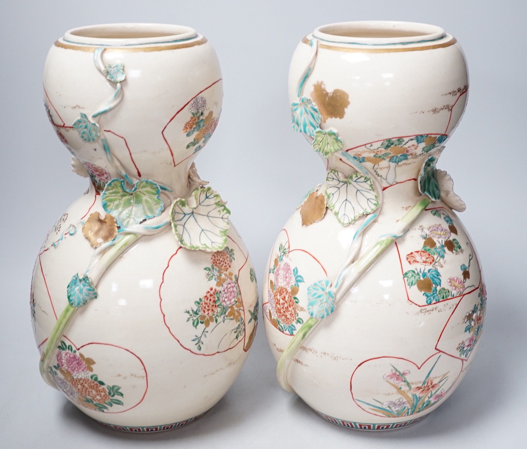 A pair of large late 19th century Satsuma pottery gourd shaped vases, each modelled with a gourd vine, 33cm tall